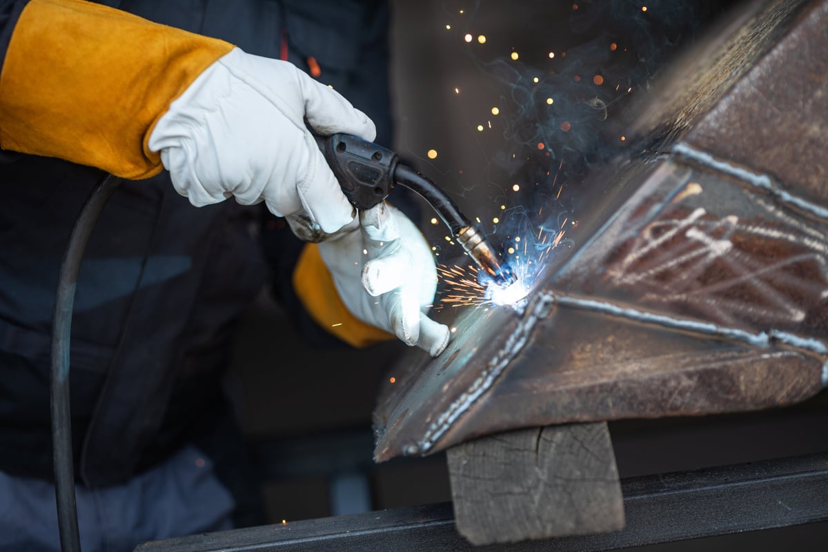 Welder joining metal parts using MIG MAG welding with protective gloves