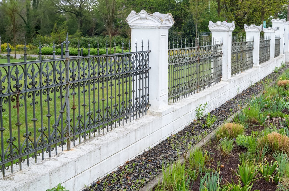 Ornate wrought iron fence bordering a vibrant garden