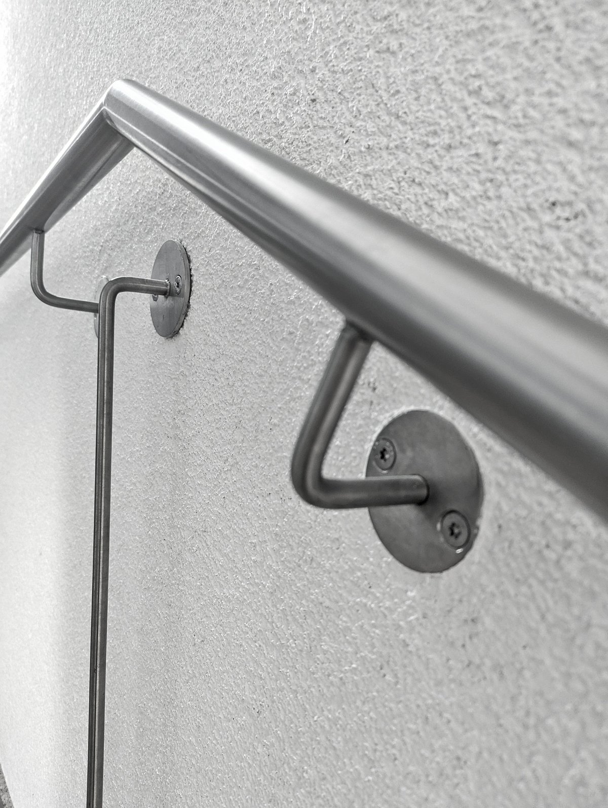 Stainless steel handrail bracket mounted on textured wall